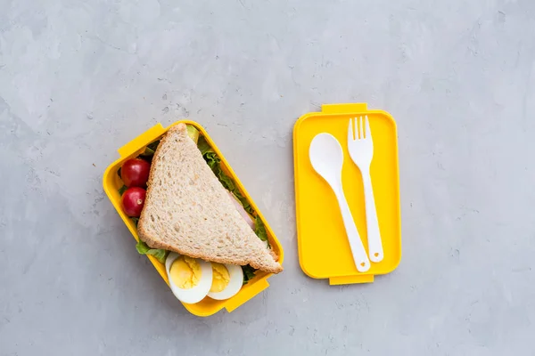 Material escolar y lonchera con sándwich y verduras. De vuelta a la escuela. Concepto de hábitos alimenticios saludables: diseño de fondo con espacio libre de texto. Composición plana, maqueta, vista superior —  Fotos de Stock