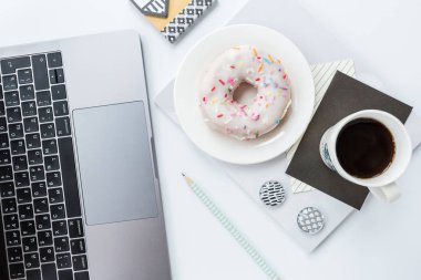 Düz yatıyordu, üst görünüm ofis masa masası çerçevesi. Çalışma alanı dizüstü bilgisayar, kalem, Notebook, kahve bardağı ve çörek beyaz arka planda. Yükü. 