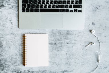 Masaüstü flatlay: laptop, Notebook, kulaklık gri mermer arka planda yatıyor. İş, finans konsepti