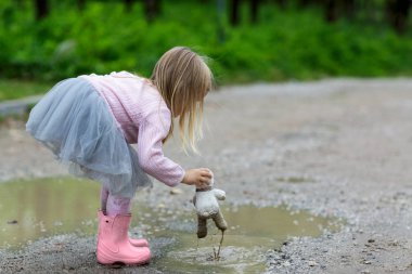 Bir tutu etek sokakta bir su birikintisi bir oyuncak ayı vuruş güzel küçük kız