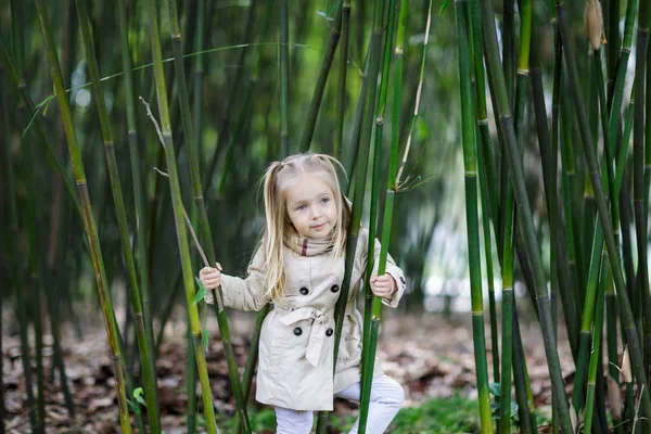 Menina bonita com cabelo loiro em pé em uma floresta de bambu e bambu tremendo — Fotografia de Stock