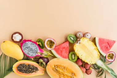 Taze egzotik meyve ve pastel turuncu arka plan tropikal palmiye yaprakları - papaya, mango, ananas, tutku meyve, ejderha meyve, üzüm, lichee, kivi, kavun. Mockup, düz yatıyordu, havai. Üstte görüntü.