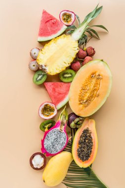 Taze egzotik meyve ve pastel turuncu arka plan tropikal palmiye yaprakları - papaya, mango, ananas, tutku meyve, ejderha meyve, üzüm, lichee, kivi, kavun. Mockup, düz yatıyordu, havai. Üstte görüntü.