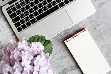 Dizüstü bilgisayar, ortanca çiçek buketi, gri mermer arka plan aksesuarları ile Ev ofis masası çalışma alanı. Düz yatıyordu, tepede, üst görünüm dekore mockup.