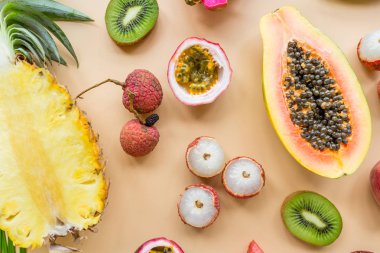 Taze egzotik meyve ve pastel turuncu arka plan tropikal palmiye yaprakları - papaya, mango, ananas, tutku meyve, ejderha meyve, üzüm, lichee, kivi, kavun. Mockup, düz yatıyordu, havai. Üstte görüntü.