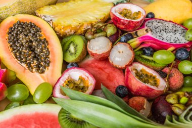 Taze egzotik meyve ve pastel turuncu arka plan tropikal palmiye yaprakları - papaya, mango, ananas, tutku meyve, ejderha meyve, üzüm, lichee, kivi, kavun. Mockup, düz yatıyordu, havai. Üstte görüntü.