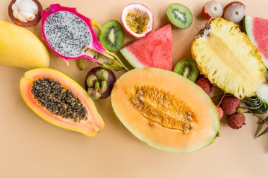 Taze egzotik meyve ve pastel turuncu arka plan tropikal palmiye yaprakları - papaya, mango, ananas, tutku meyve, ejderha meyve, üzüm, lichee, kivi, kavun. Mockup, düz yatıyordu, havai. Üstte görüntü.