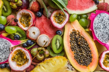 Taze egzotik meyve ve pastel turuncu arka plan tropikal palmiye yaprakları - papaya, mango, ananas, tutku meyve, ejderha meyve, üzüm, lichee, kivi, kavun. Mockup, düz yatıyordu, havai. Üstte görüntü.