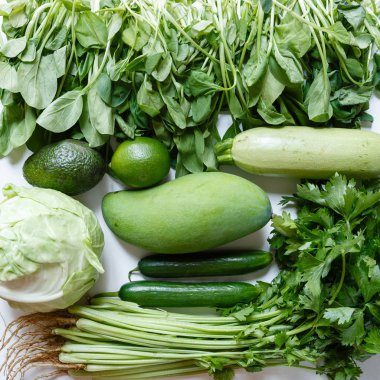 Havai, kereviz, avokado, lahana, mango, salatalık, ıspanak, kireç, kabak rustik beyaz arka plan taze yeşil sebze çeşitli. Sağlıklı, vejetaryen konsepti. Düz döşeme, üst görünüm
