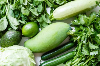 Havai, kereviz, avokado, lahana, mango, salatalık, ıspanak, kireç, kabak rustik beyaz arka plan taze yeşil sebze çeşitli. Sağlıklı, vejetaryen konsepti. Düz döşeme, üst görünüm