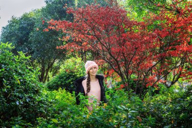 Kırmızı yaprakları ile akçaağaç ağacı yakın parkta ayakta şık genç kadın. Sonbahar ve Güz sezonu