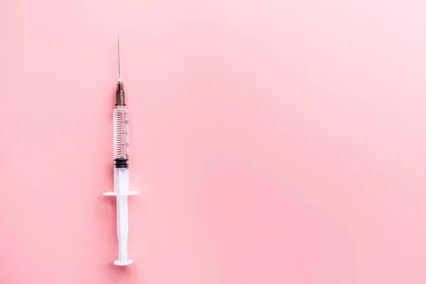 Jeringa médica sobre fondo rosa, salud y concepto de vacunación. Colocación plana, maqueta, techo, vista superior y espacio de copia . — Foto de Stock
