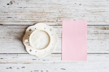 Kahvaltı için sabah kahve fincanı, beyaz ahşap masa üzerinde pembe kağıt boş, üst görünümü, düz yatıyordu tarzı. Kadın çalışma masası. Mockup, genel merkez