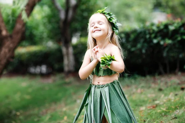 Menina loira bonito em traje de carnaval feito de grama verde ao ar livre. Criança elegante pronta para a festa de Halloween — Fotografia de Stock