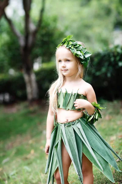 Cute little girl blondynka w stroju karnawału wykonane z zielonej trawy na zewnątrz. Stylowy dzieciak gotowy na halloween party — Zdjęcie stockowe