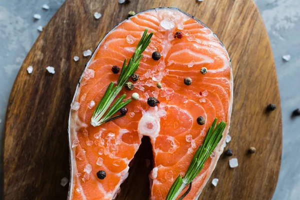 Fresh raw salmon fish steak with spices on dark stone background. Creative layout made of fish, top view, flat lay, mockup, overhead. Healthy food concept — Stock Photo, Image