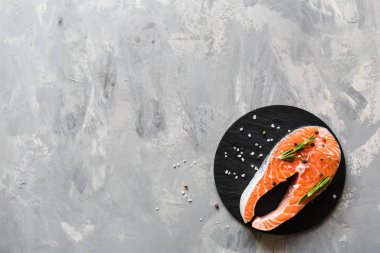 Koyu taş arka plan üzerinde baharat ile taze çiğ somon balık biftek. Balık, üst görünüm, düz yatıyordu, mockup, havai yapılmış Yaratıcı düzeni. Sağlıklı gıda kavramı