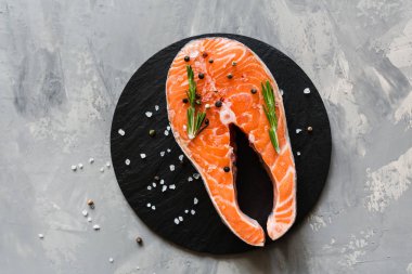 Koyu taş arka plan üzerinde baharat ile taze çiğ somon balık biftek. Balık, üst görünüm, düz yatıyordu, mockup, havai yapılmış Yaratıcı düzeni. Sağlıklı gıda kavramı