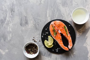 Koyu taş arka plan üzerinde baharat ile taze çiğ somon balık biftek. Balık, üst görünüm, düz yatıyordu, mockup, havai yapılmış Yaratıcı düzeni. Sağlıklı gıda kavramı