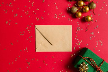 Noel kompozisyonu. Zarf, paket hediye, kırmızı arka planda altın konfetili oyuncaklar. Yeni yıl konsepti. Kutlama kartı, xmas kutlaması 2020. Düz konum, üst görünüm, kopyalama alanı, modelleme