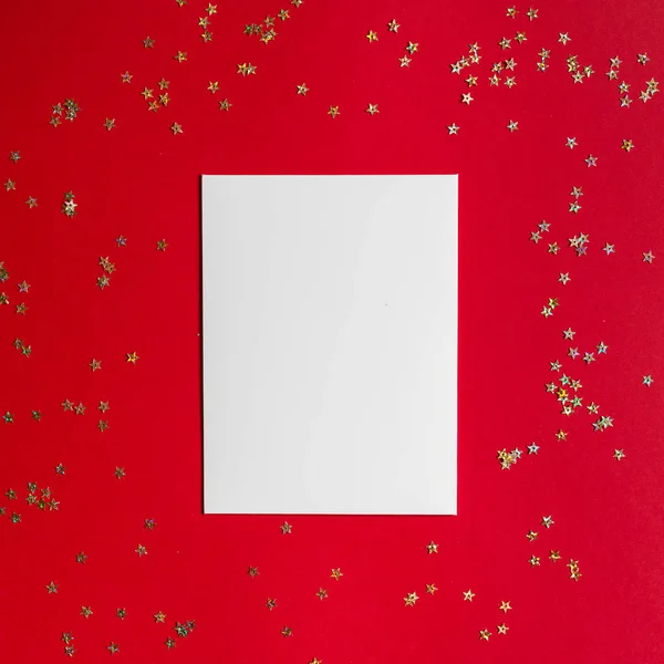 Χριστουγεννιάτικη σύνθεση. Λευκό λευκό λευκό χαρτί σε κόκκινο φόντο με χρυσά κομφετί. Χειμερινές διακοπές, έννοια του νέου έτους. Ευχετήρια κάρτα, Χριστουγεννιάτικη γιορτή 2020. Επίπεδη lay, top view, αντιγραφή χώρου, μακιγιάρισμα — Φωτογραφία Αρχείου
