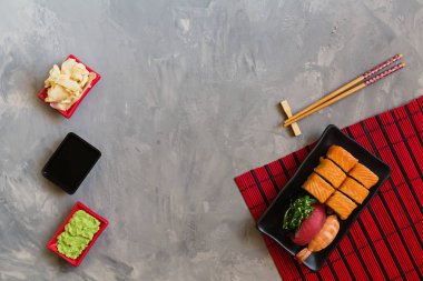 Suşi, zencefil, soya sosu, wasabi kase ve beton gri arka plan üzerinde çubukları ile geleneksel japon boş üst görünümü, kopya alanı, mockup, düz yatıyordu. Online asya gıda dağıtım konsepti