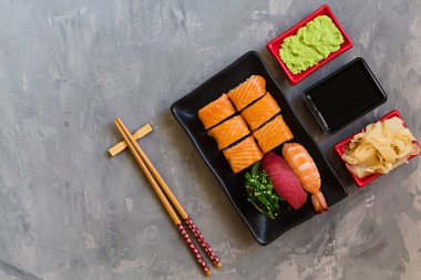 Suşi, zencefil, soya sosu, wasabi kase ve beton gri arka plan üzerinde çubukları ile geleneksel japon boş üst görünümü, kopya alanı, mockup, düz yatıyordu. Online asya gıda dağıtım konsepti