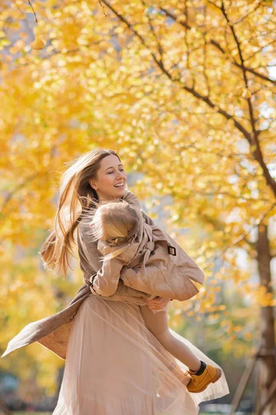 Mother and daughter in autumn park. Family lifestyle. Happy mother and child spend time together outdoor. Fall season