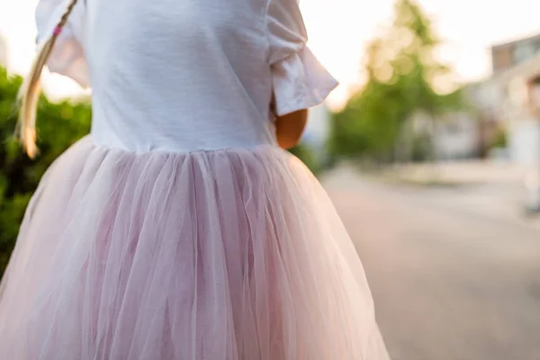 Malá dívka v růžové sukně stojí venku zezadu — Stock fotografie
