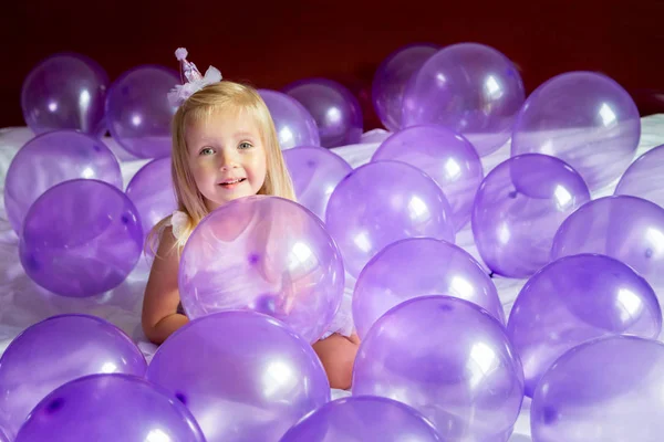 Roztomilé holčička ve stylových šatech slaví narozeniny den s fialovými balónky — Stock fotografie