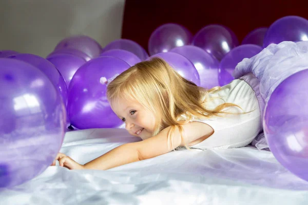 Mor balonlarla doğum gününü kutlayan şık elbiseli şirin küçük kız. — Stok fotoğraf