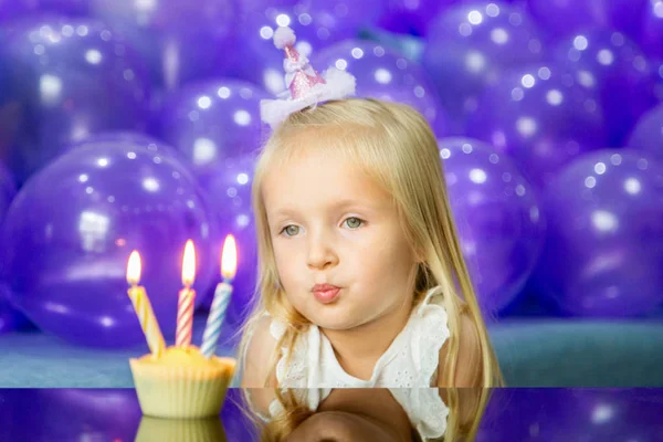 Süßes kleines Mädchen in stylischem Kleid feiert Geburtstag mit lila Luftballons — Stockfoto