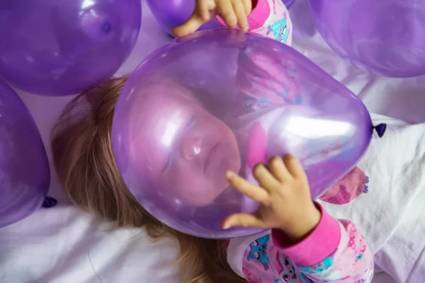 Menina bonito em pijama elegante celebrando dia de aniversário com balões roxos — Fotografia de Stock