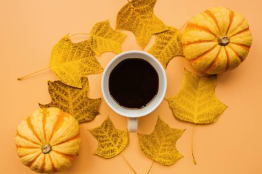 Sonbahar çerçeve kabak, kahve fincan ve turuncu arka plan üzerinde düşmüş yaprakları yapılmış. Sonbahar, Cadılar Bayramı ve Şükran Günü konsepti. Styled stok düz döşeme fotoğraf. Üst te. Metniniz için boş alan.