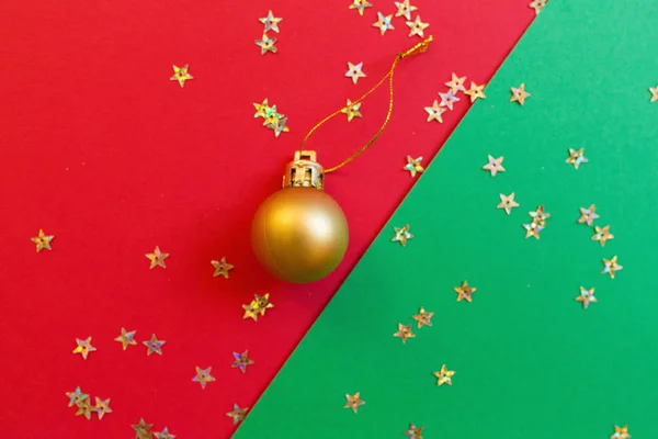 Різдвяна композиція. Золота іграшка на червоно-зеленому тлі з золотим конфетті. концепція нового року. Вітальна листівка, святкування Різдва 2020 року. Плоский простір, вид зверху, простір для копіювання, макет — стокове фото