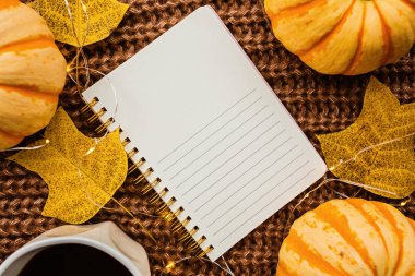 Sonbahar çerçeve kabak, dizüstü bilgisayar, kahve fincan ve kahverengi örme kazak üzerine düşmüş yaprakları yapılmış. Sonbahar, Cadılar Bayramı ve Şükran Günü konsepti. Üst te. Metniniz için boş alan.