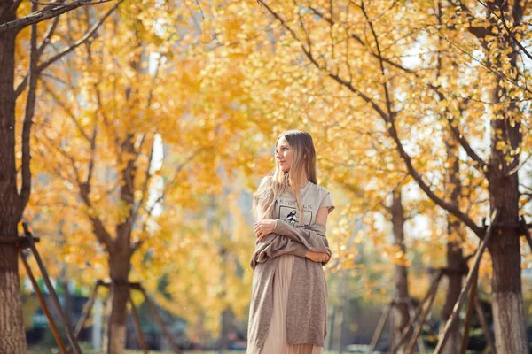 Portrait d'une belle jeune femme aux longs cheveux blonds profitant de l'automne dans le parc. Arrière-plan de ginkgo au feuillage jaune. Saison d'automne . — Photo