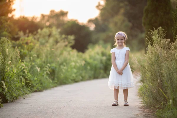 Portret urocza dziewczynka z długimi blond włosami w parku słoneczny letni dzień. Piękne dziecko. Szczęśliwy uśmiechnięty dzieciak, dzień dzieciństwa, koncepcja edukacyjna — Zdjęcie stockowe