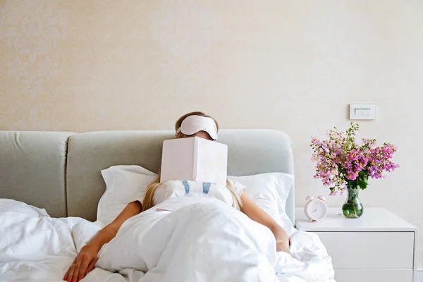 Bella felice giovane donna dormire con notebook a letto. Ritratto di ragazza bionda con benda in camera da letto . — Foto Stock
