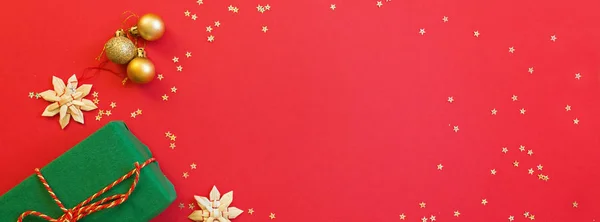 Різдвяна композиція. Подарункова коробка, золоті іграшки на червоному тлі. концепція нового року. Вітальна листівка, святкування Різдва 2020 року. Плоский простір, вид зверху, місце для копіювання, макет. Банер для Інтернету — стокове фото