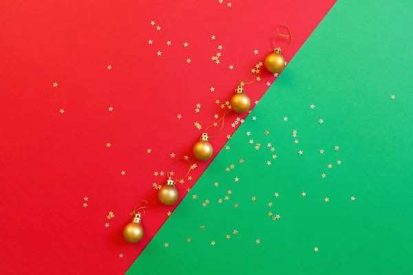 Різдвяна композиція. Золота іграшка на червоно-зеленому тлі з золотим конфетті. концепція нового року. Вітальна листівка, святкування Різдва 2020 року. Плоский простір, вид зверху, простір для копіювання, макет — стокове фото