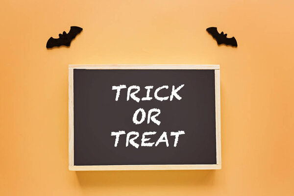 Trick or treat decoration on orange background. Halloween decoration with bats. Flat lay, top view, mockup, template, overhead. Holiday concept. Idea for website banner design with copy space