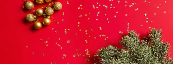 Різдвяні іграшки та гілки ялиці на червоному тлі з золотим конфетті. концепція нового року. Прапор для веб-дизайну. Вітальна листівка, святкування Різдва 2020 року. Плоский простір, вид зверху, простір для копіювання, макет — стокове фото