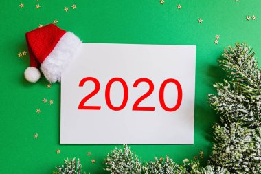 Kırmızı Noel Baba şapkalı boş bir kağıt, yeşil arka planda konfetili noel ağacı dalları. Yeni yıl konsepti. Kutlama kartı, xmas kutlaması 2020. Düz konum, şablon, üst görünüm, kopyalama alanı, modelleme