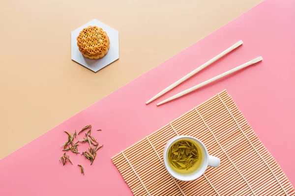 Flat lay of Chinese Festival dessert, Mid Autumn Festival Moon cake on colorful background with green tea and chopsticks. Top view, copy space, mockup, overhead, template
