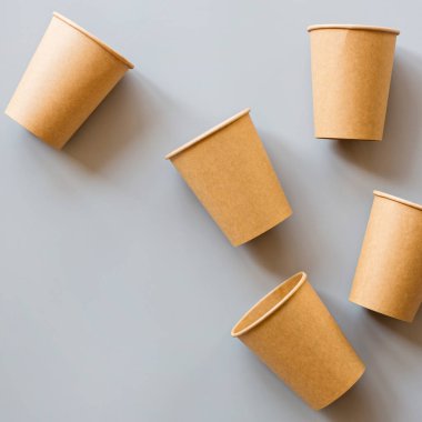 Eko doğal kağıt kahve fincanları gri arka planda yatıyordu. Sürdürülebilir yaşam tarzı kavramı. sıfır atık, plastiksiz eşyalar. Plastik kirliliğini durdurun. Üst görünüm, genel görünüm, model, şablon