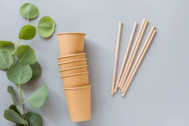 Eko doğal kağıt kahve fincanı ve pipetler gri arka planda yatıyordu. Sürdürülebilir yaşam tarzı kavramı. sıfır atık, plastiksiz eşyalar. Plastik kirliliğini durdurun. Üst görünüm, genel görünüm, model, şablon