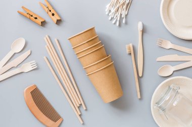 Çevresel doğal kağıt bardaklar, pipetler, diş fırçası düz gri arka planda yatıyordu. Sürdürülebilir yaşam tarzı kavramı. sıfır atık, plastiksiz eşyalar. Plastik kirliliğini durdurun. Üst görünüm, genel görünüm, şablon, model.