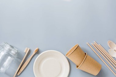 Çevresel doğal kağıt bardaklar, pipetler, diş fırçası düz gri arka planda yatıyordu. Sürdürülebilir yaşam tarzı kavramı. sıfır atık, plastiksiz eşyalar. Plastik kirliliğini durdurun. Üst görünüm, genel görünüm, şablon, model.