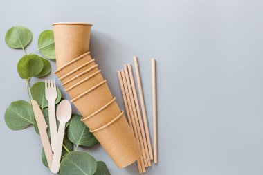 Çevresel doğal kağıt bardaklar, pipetler, tahta çatal bıçaklar gri arka planda yatıyordu. Sürdürülebilir yaşam tarzı kavramı. sıfır atık, plastiksiz eşyalar. Plastik kirliliğini durdurun. Üst görünüm, genel görünüm, şablon, model.